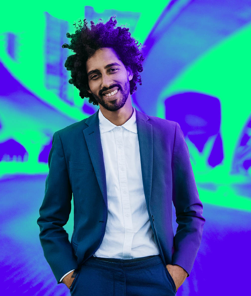 A guy with curly hair and a suit is smiling