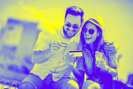 Happy couple paying on line with credit card on the street